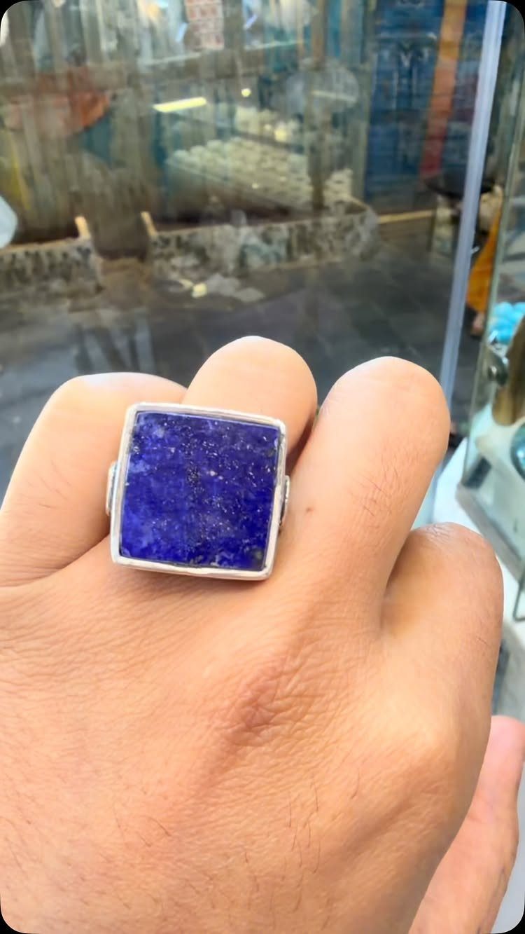 Silver ring with a square blue lapis lazuli stone worn on a finger