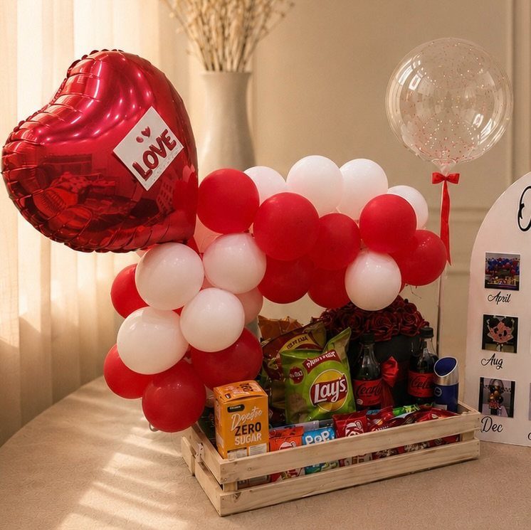 Gift crate with red and white balloons and snacks for a romantic anniversary.