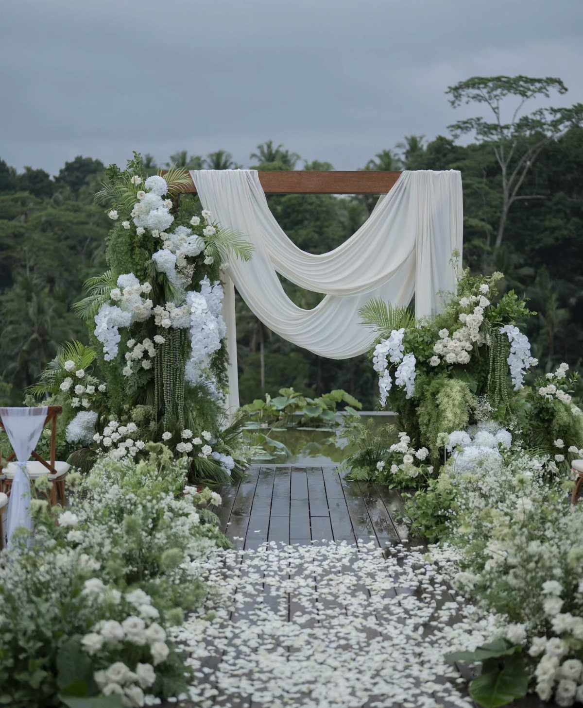 Wedding altar with white fabric and flowers on a wooden deck in Bali.