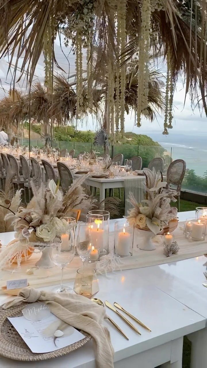Wedding reception table with candles and pampas grass under a thatched roof