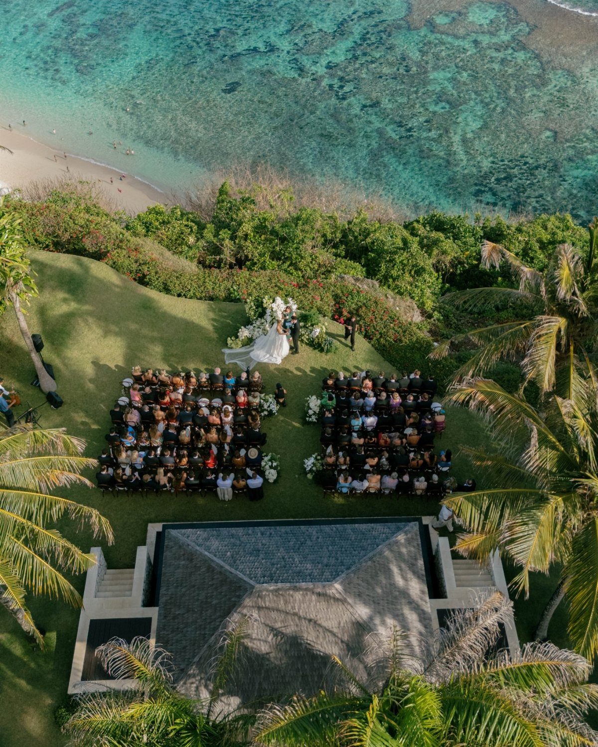 Outdoor wedding ceremony on a green cliffside overlooking a turquoise ocean in Bali.