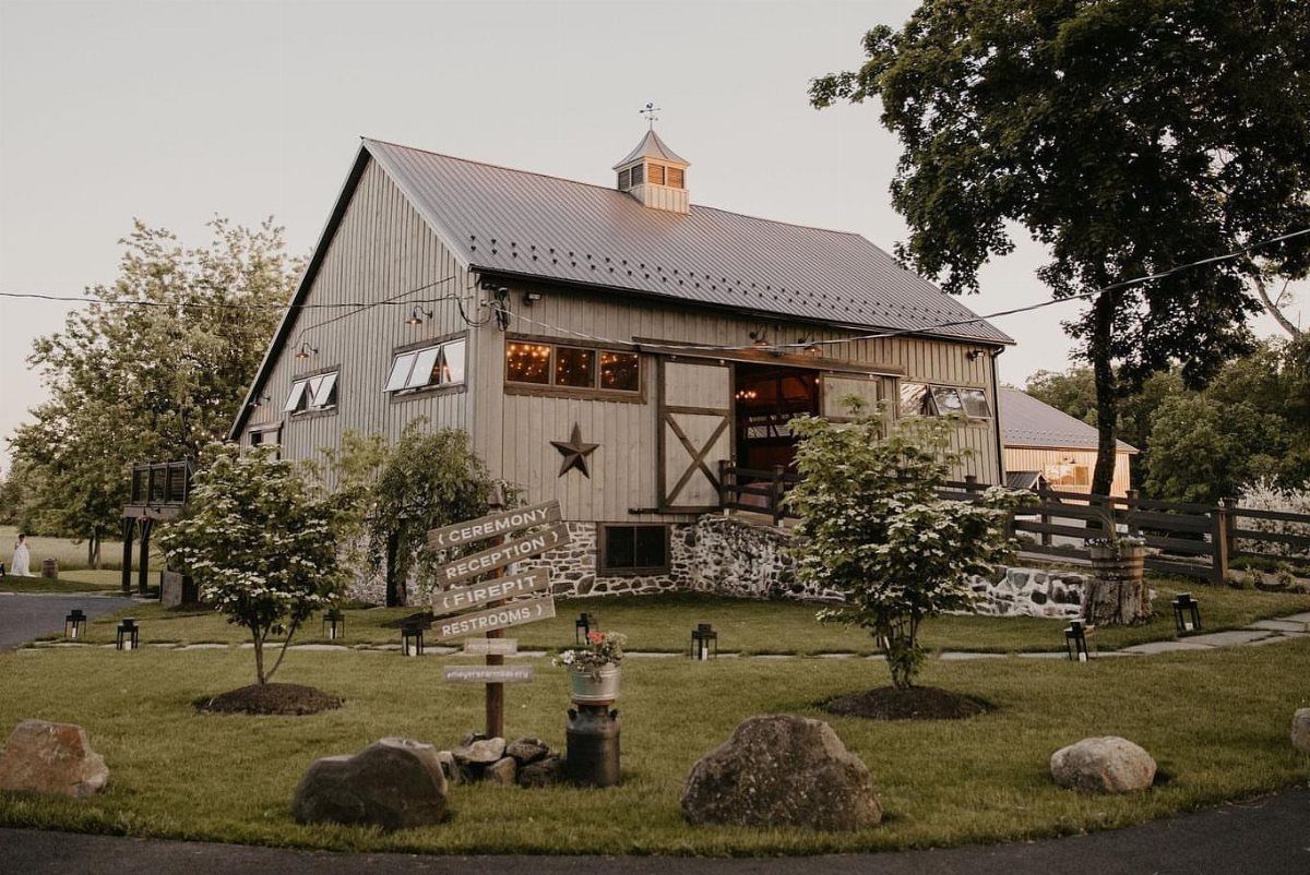 Grey wooden barn with metal roof and star decoration on a grassy lawn