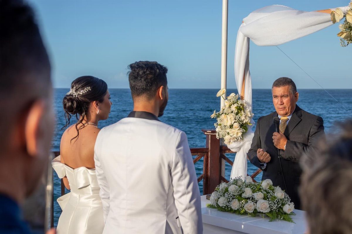 Bride and groom standing before an officiant during a beachside wedding ceremony.