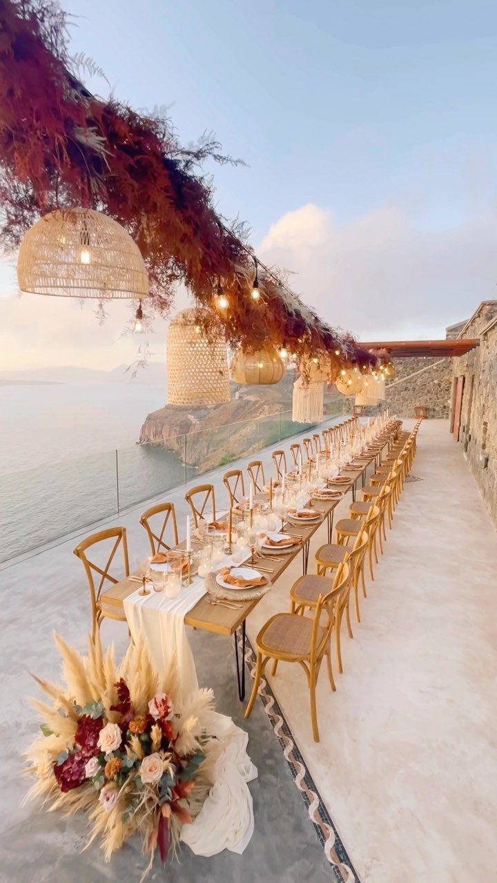 Long wedding table with rusty terra cotta florals overlooking a coastal ocean view.