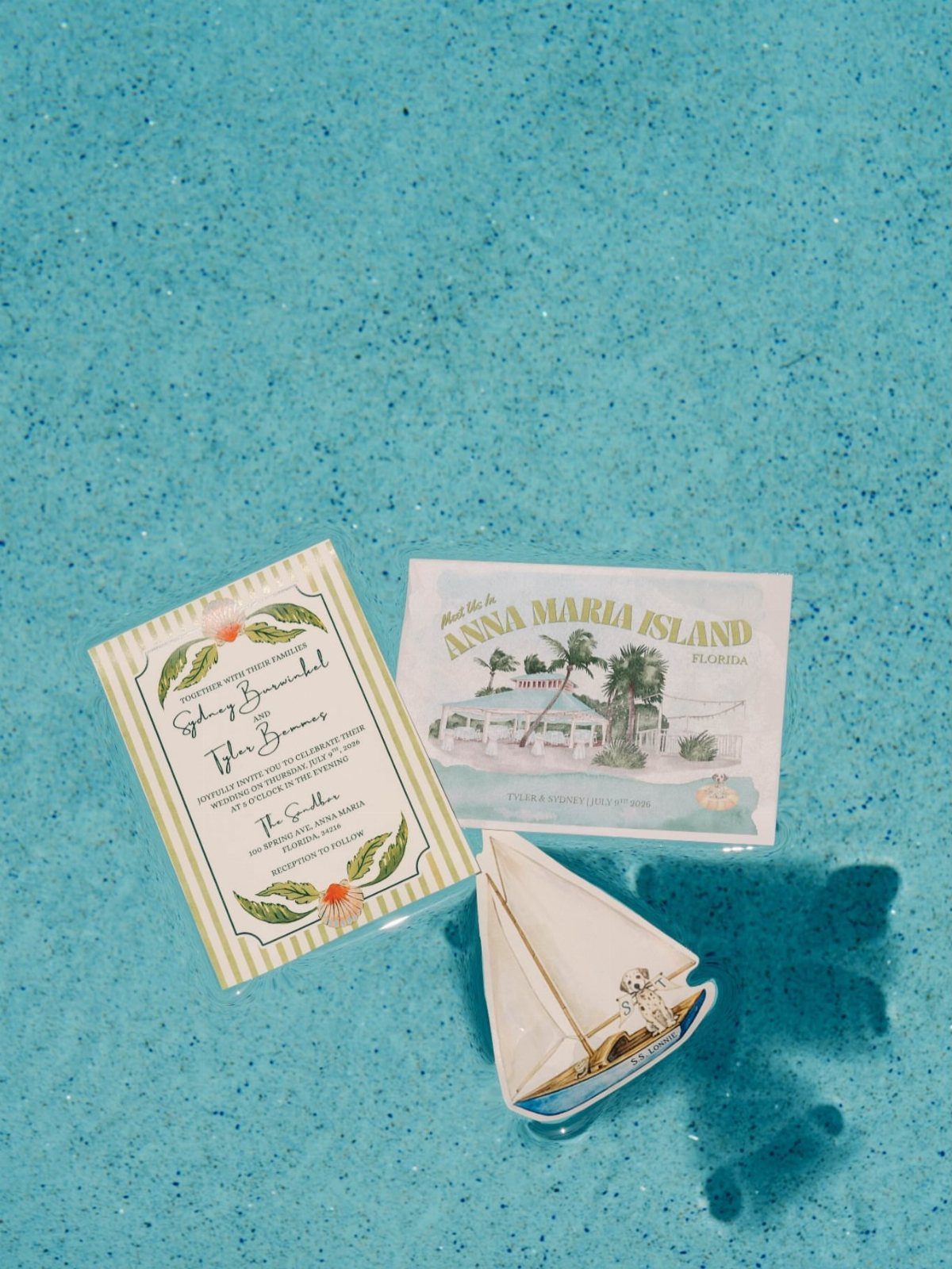 Wedding invitation and postcard with a toy sailboat on turquoise beach sand