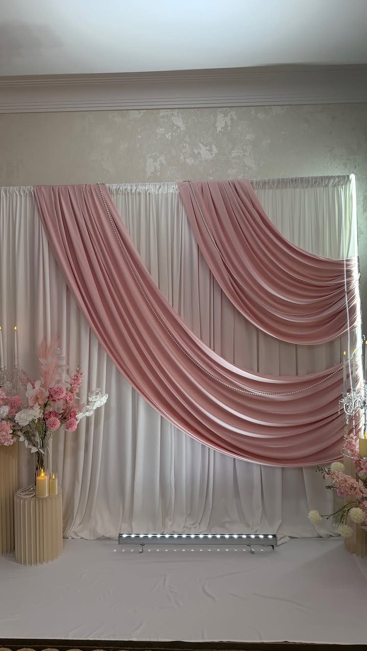 White and pink draped fabric backdrop with pink flowers and candles for wedding