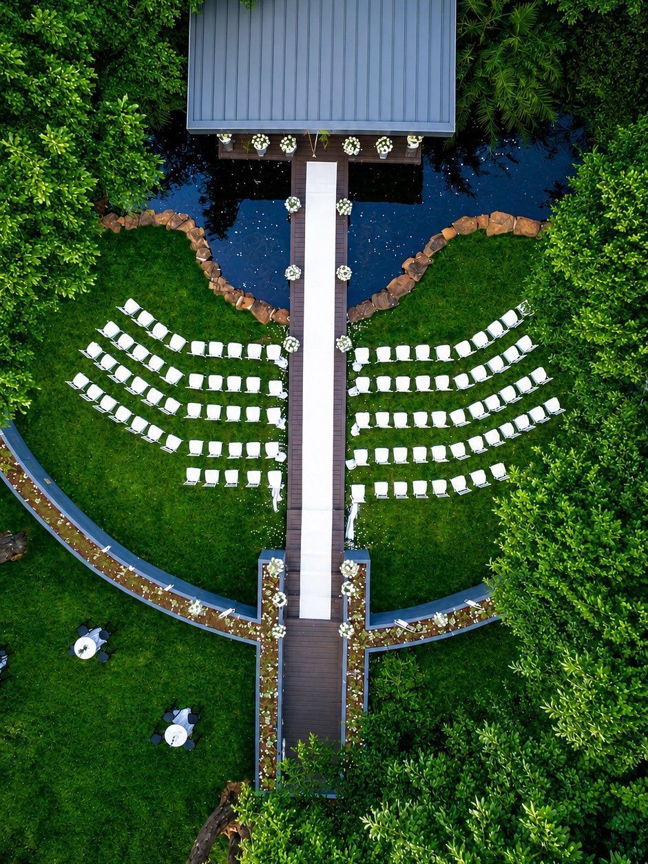 Outdoor wedding ceremony setup with white chairs and aisle on a green lawn