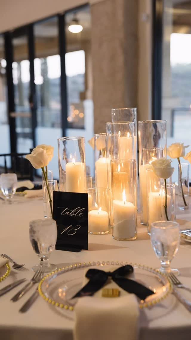 Wedding table setting with white pillar candles in glass vases and white roses.