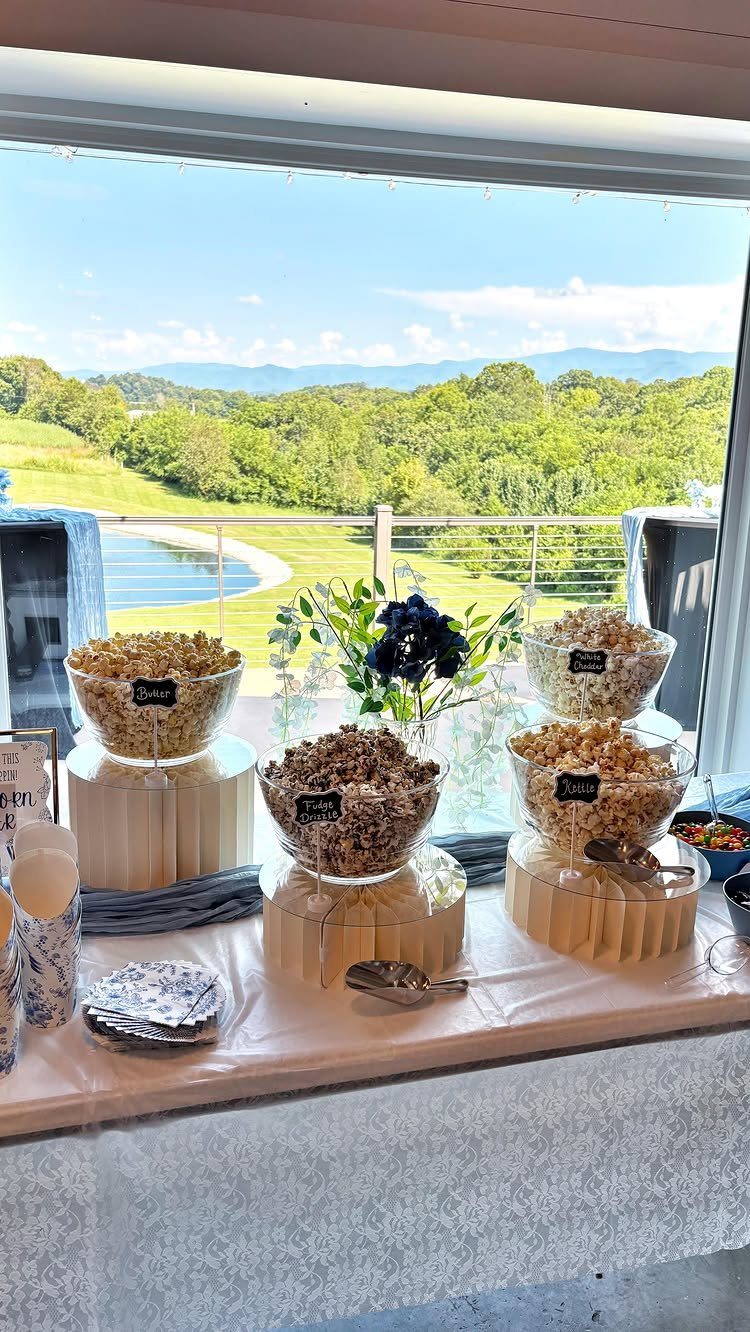 Popcorn bar with four glass bowls of popcorn on a white table.