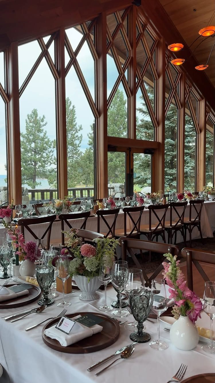 Wedding reception table setting inside a wooden hall overlooking a pine forest