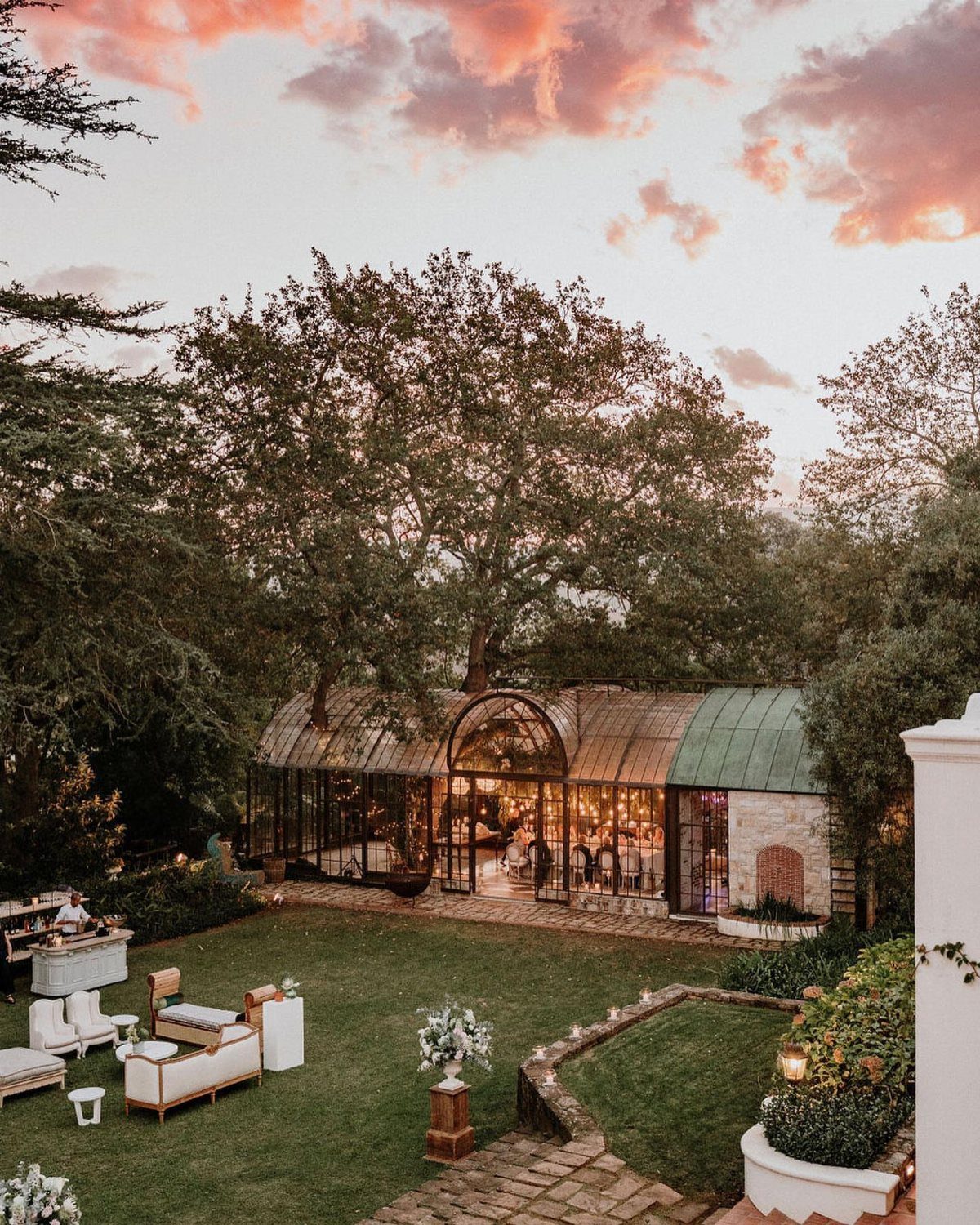 Glass conservatory wedding venue on a green lawn under a sunset sky