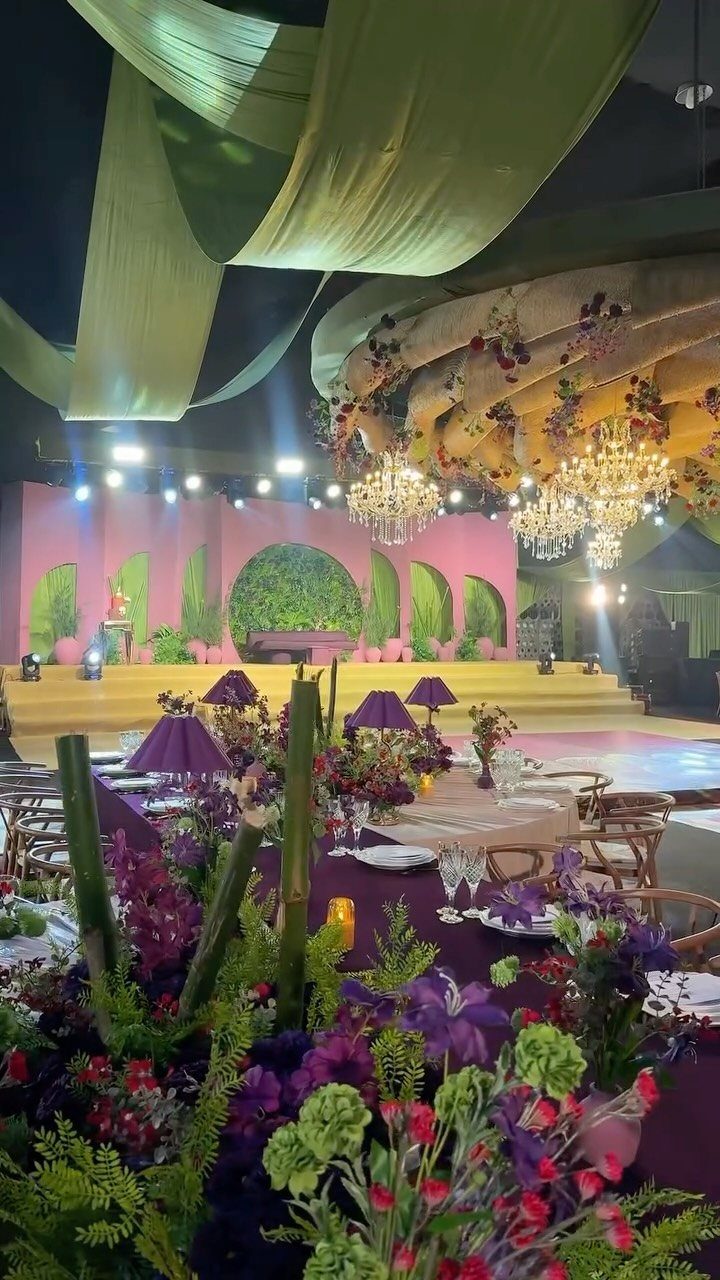 Green fabric drapes and crystal chandeliers hanging above a decorated event space.