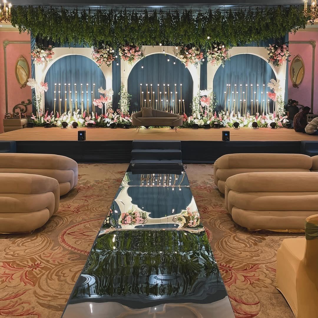 Lavish event stage with floral decor and plush beige lounge seating on patterned carpet