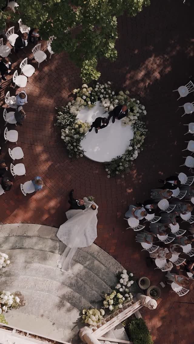Circular floral ceremony setup with curved guest seating on a brick patio.