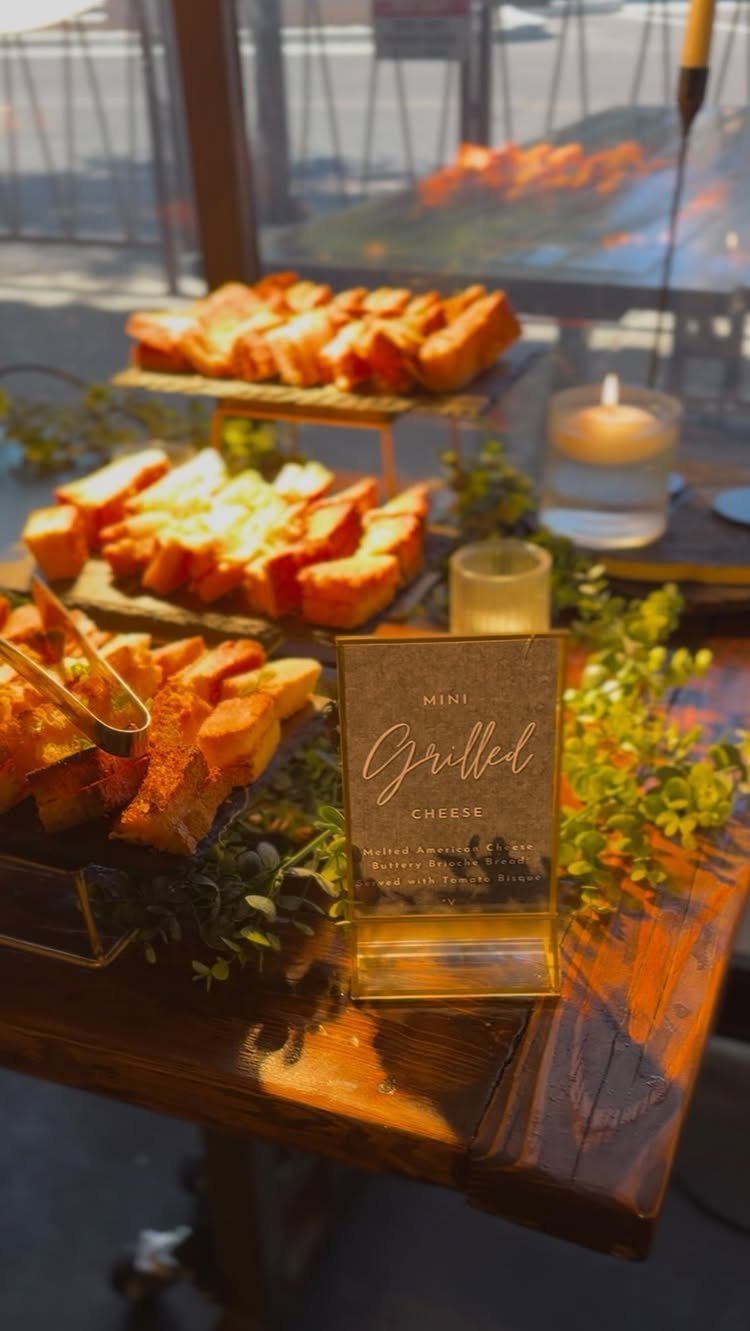 Grilled cheese sandwiches on wooden platters with a menu sign and greenery.