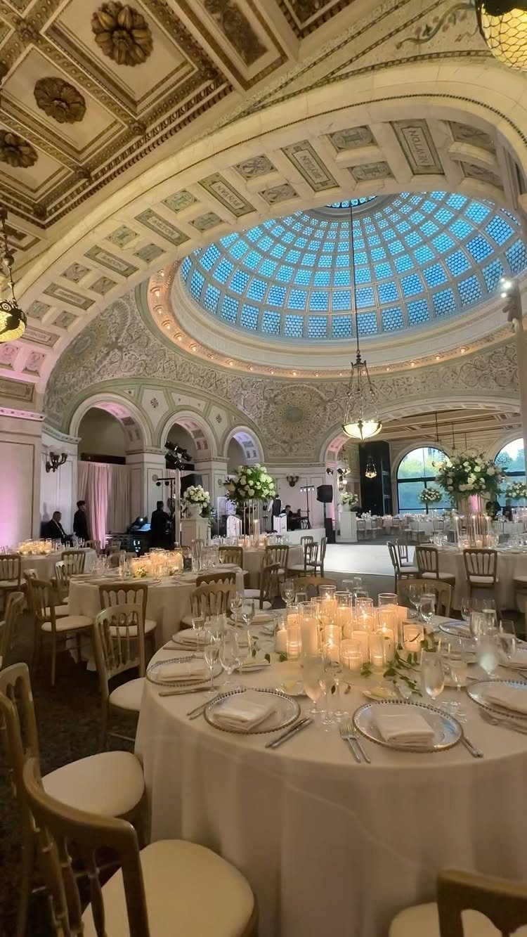 Wedding reception tables under a grand ornate ceiling with a blue glass dome.