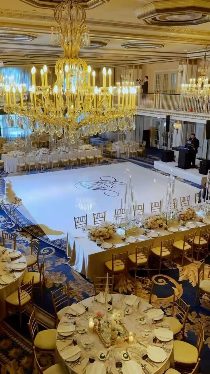Opulent ballroom with gold chandeliers, white dance floor, and elegant wedding table settings.