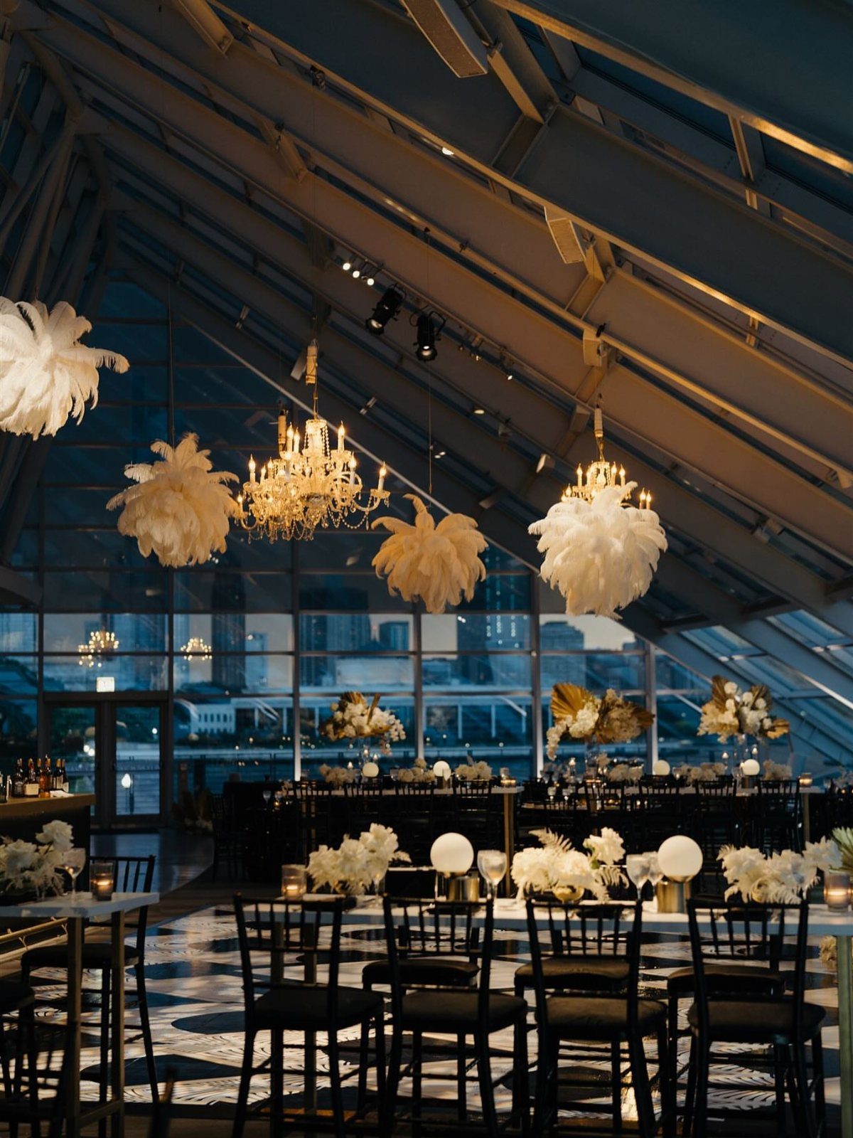Modern event venue with glass walls overlooking a city skyline at twilight.