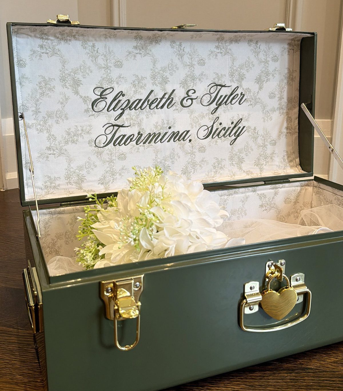 Green metal keepsake box with gold lock and personalized wedding text inside lid.
