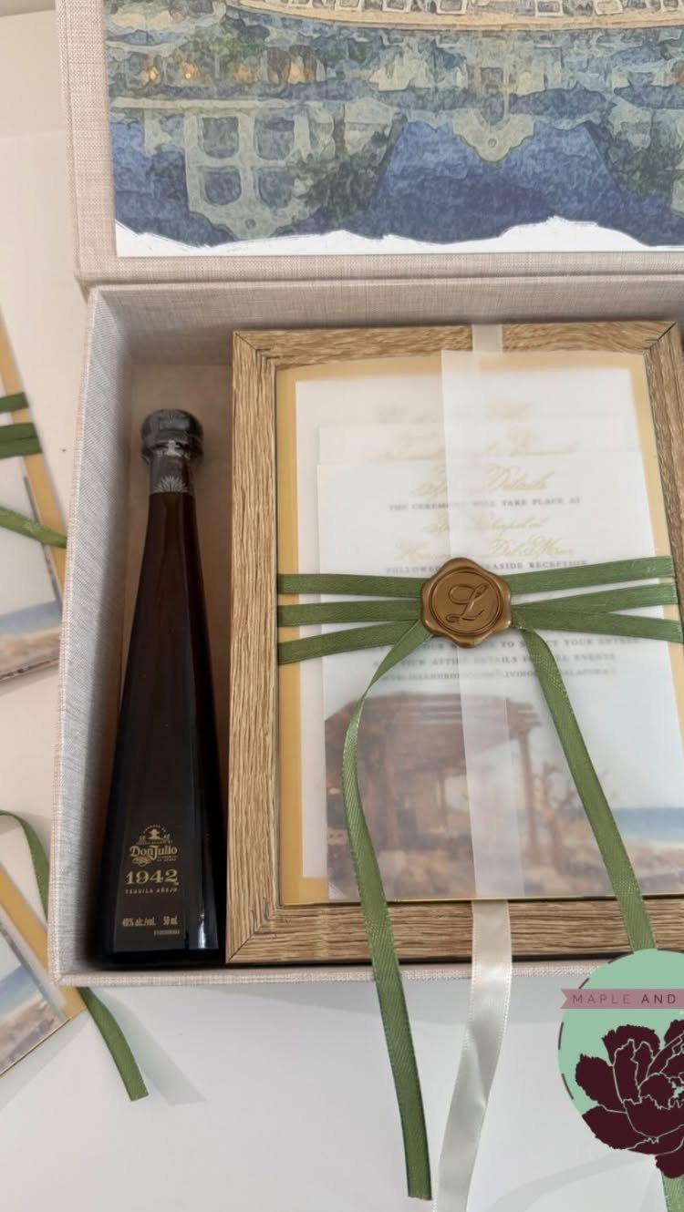 Luxury wedding invitation in a linen box with a green ribbon and tequila bottle.