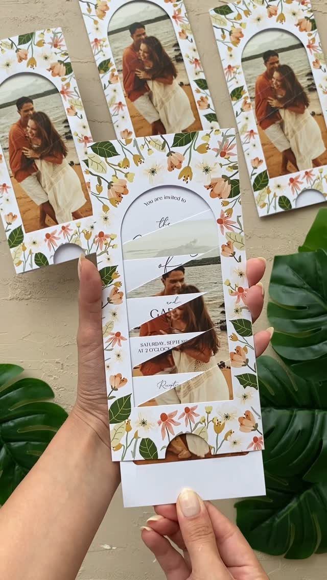 Floral wedding invitation with a sliding photo of a couple on a beach.