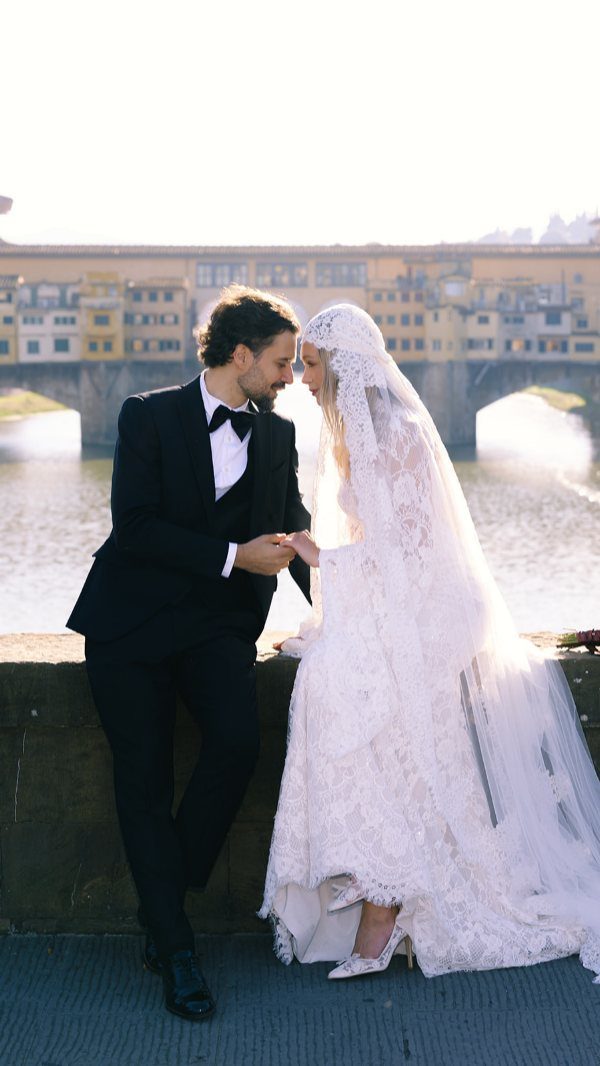 Bride and groom posing on a bridge with the Ponte Vecchio in Florence