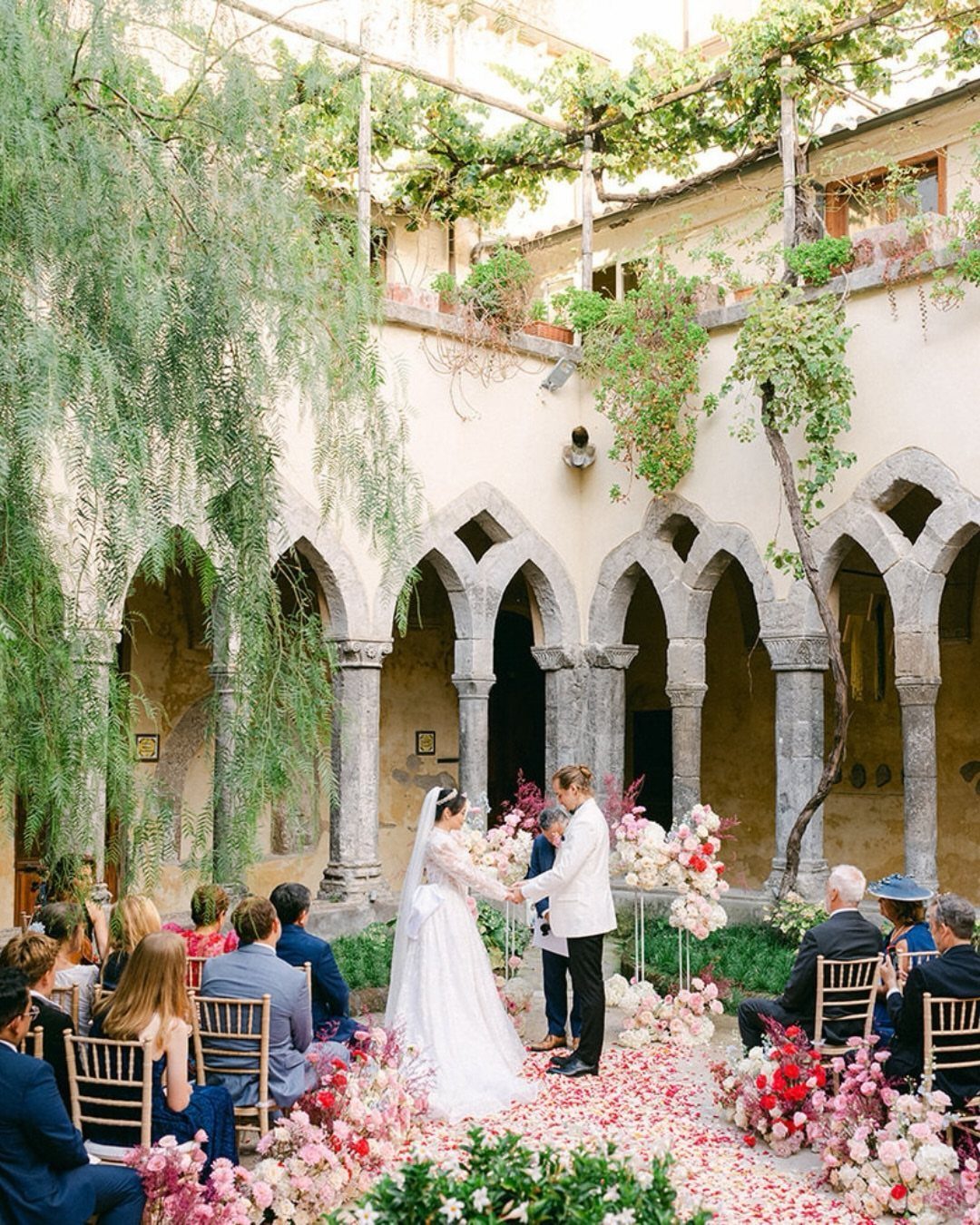 Bride and groom holding hands during a wedding ceremony in a stone courtyard