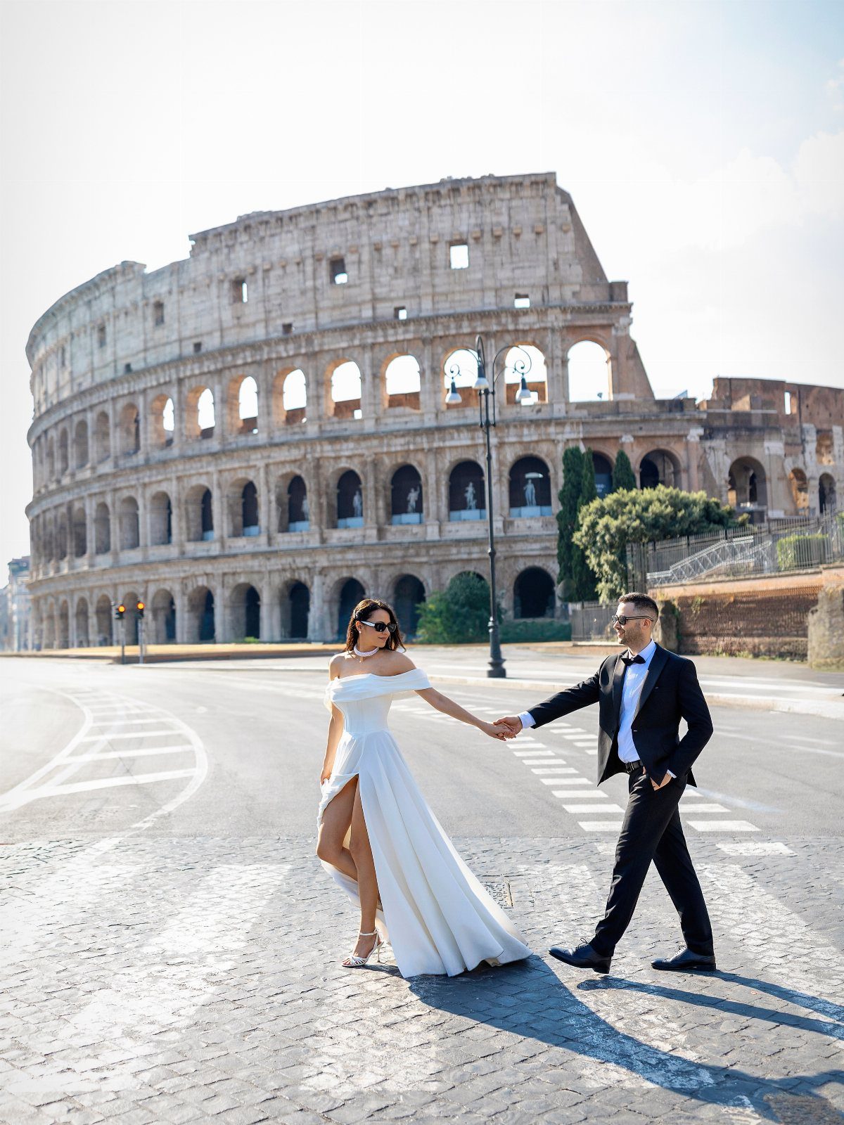 Wedding couple holding hands and walking in front of the Colosseum in Rome.