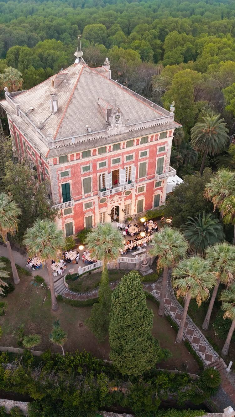 Red Italian villa with palm trees and outdoor dining area in Portofino