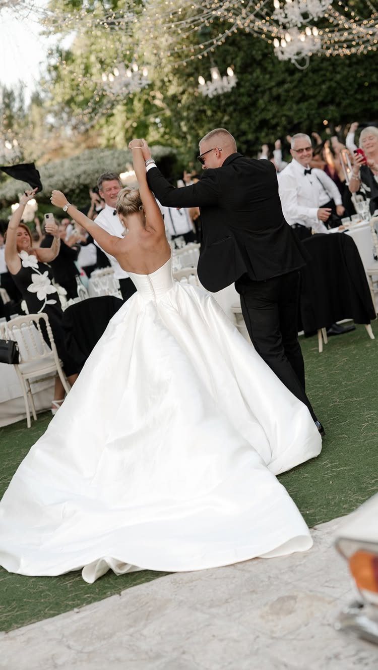 Bride and groom dancing their first dance outdoors surrounded by wedding guests.