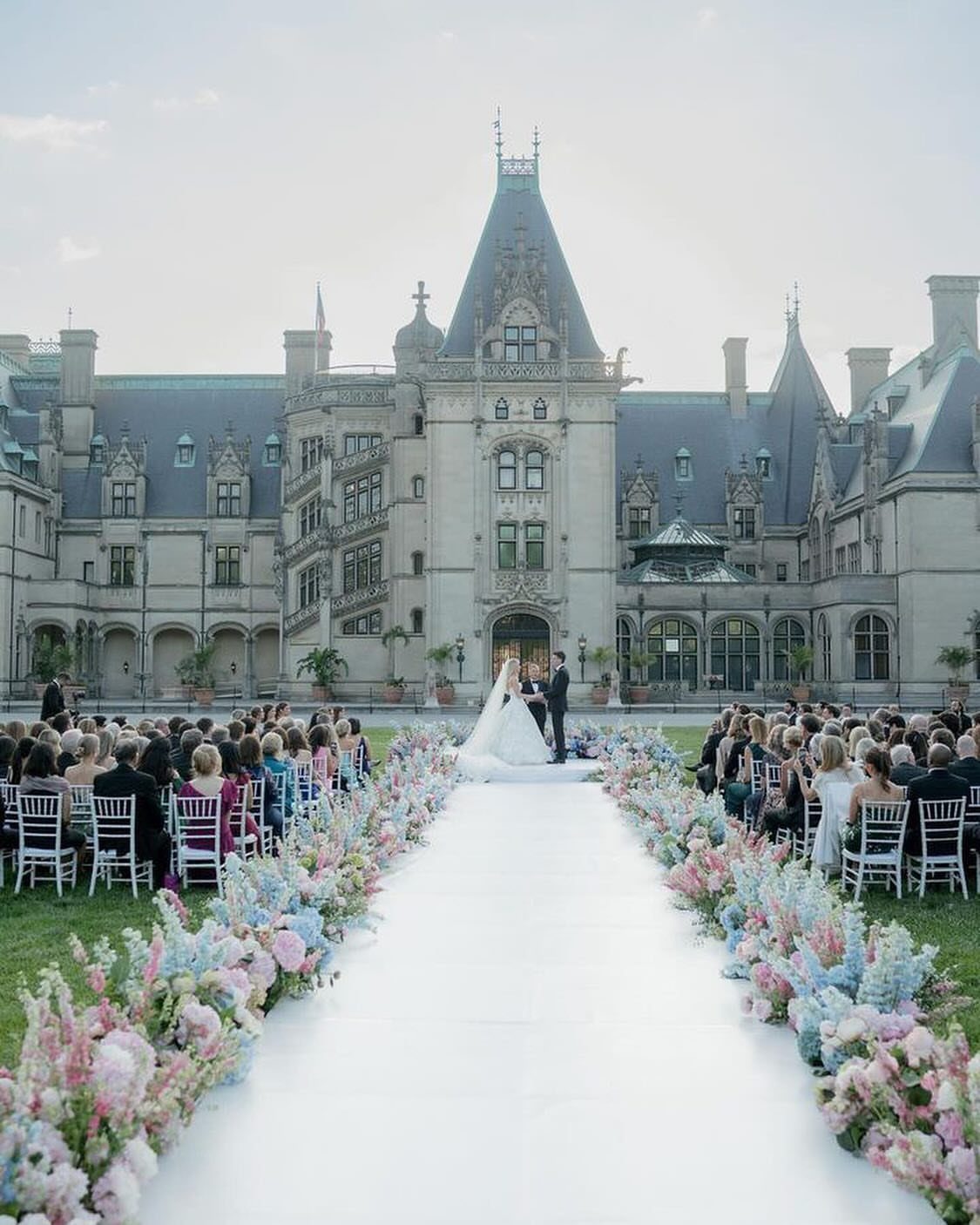 Wedding ceremony with a white floral aisle in front of the Biltmore Estate.