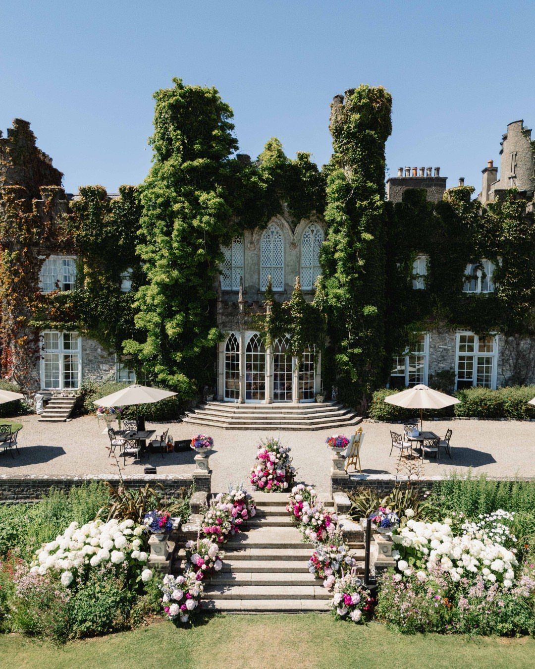 Ivy-covered stone castle with floral decorations on steps for a wedding venue.