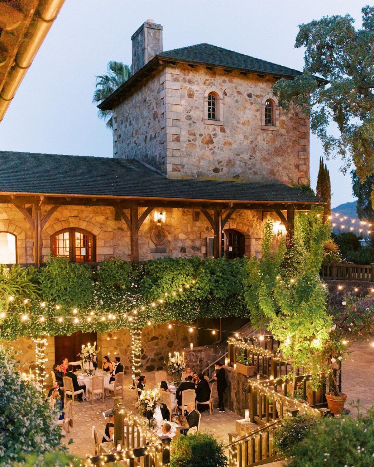 Outdoor dinner party with fairy lights at a rustic stone estate venue.