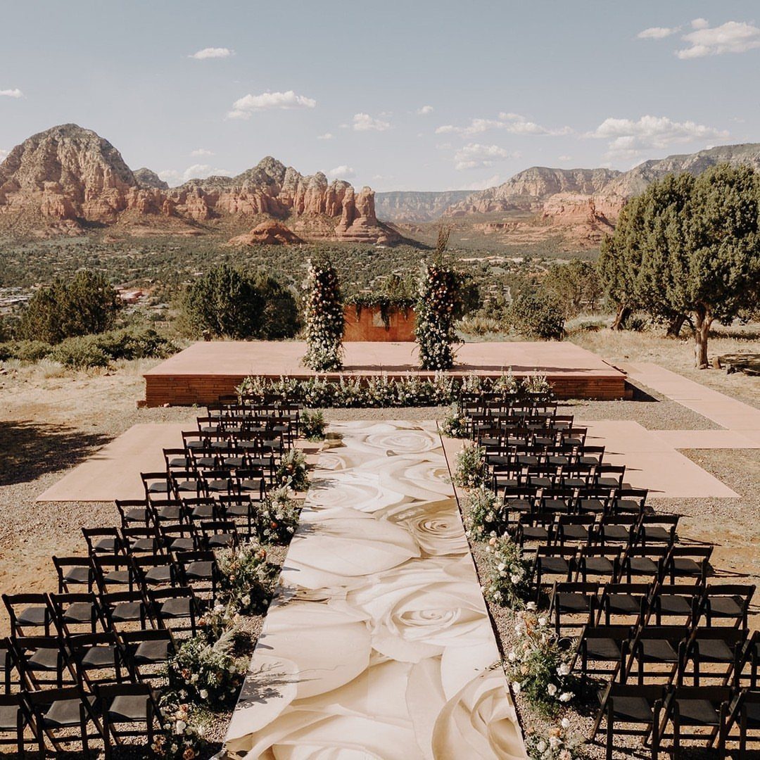 Wedding ceremony setup with a floral aisle runner against Sedona red rock mountains.