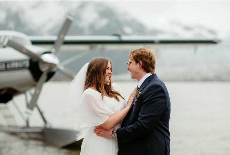Bride and groom smiling in front of a float plane by a lake