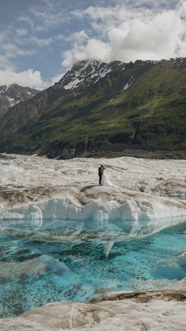 Wedding couple embracing on a white glacier with turquoise water and mountains.