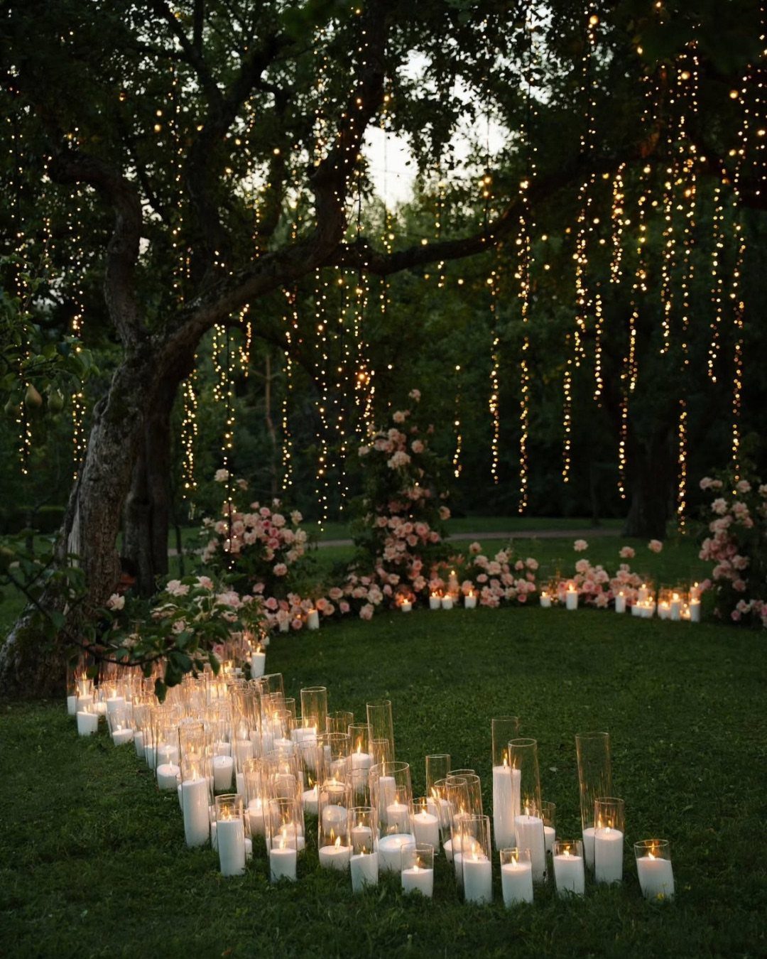 Candlelit path and hanging fairy lights under a tree for a forest wedding.