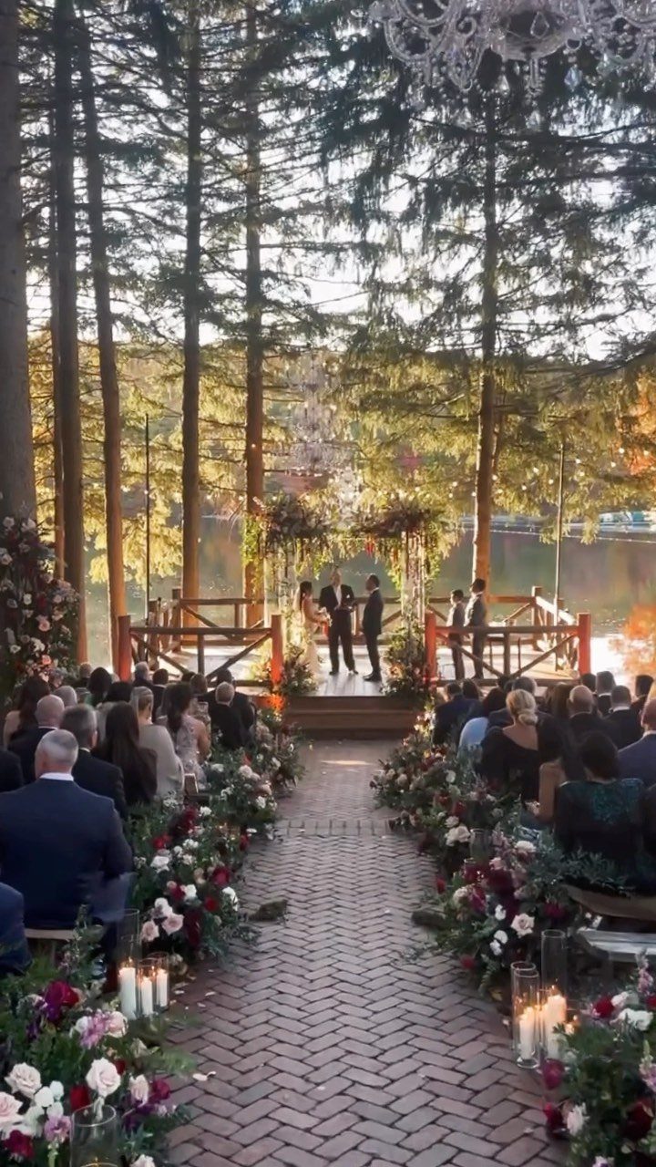 Wedding ceremony on a wooden deck by a lake surrounded by tall forest trees