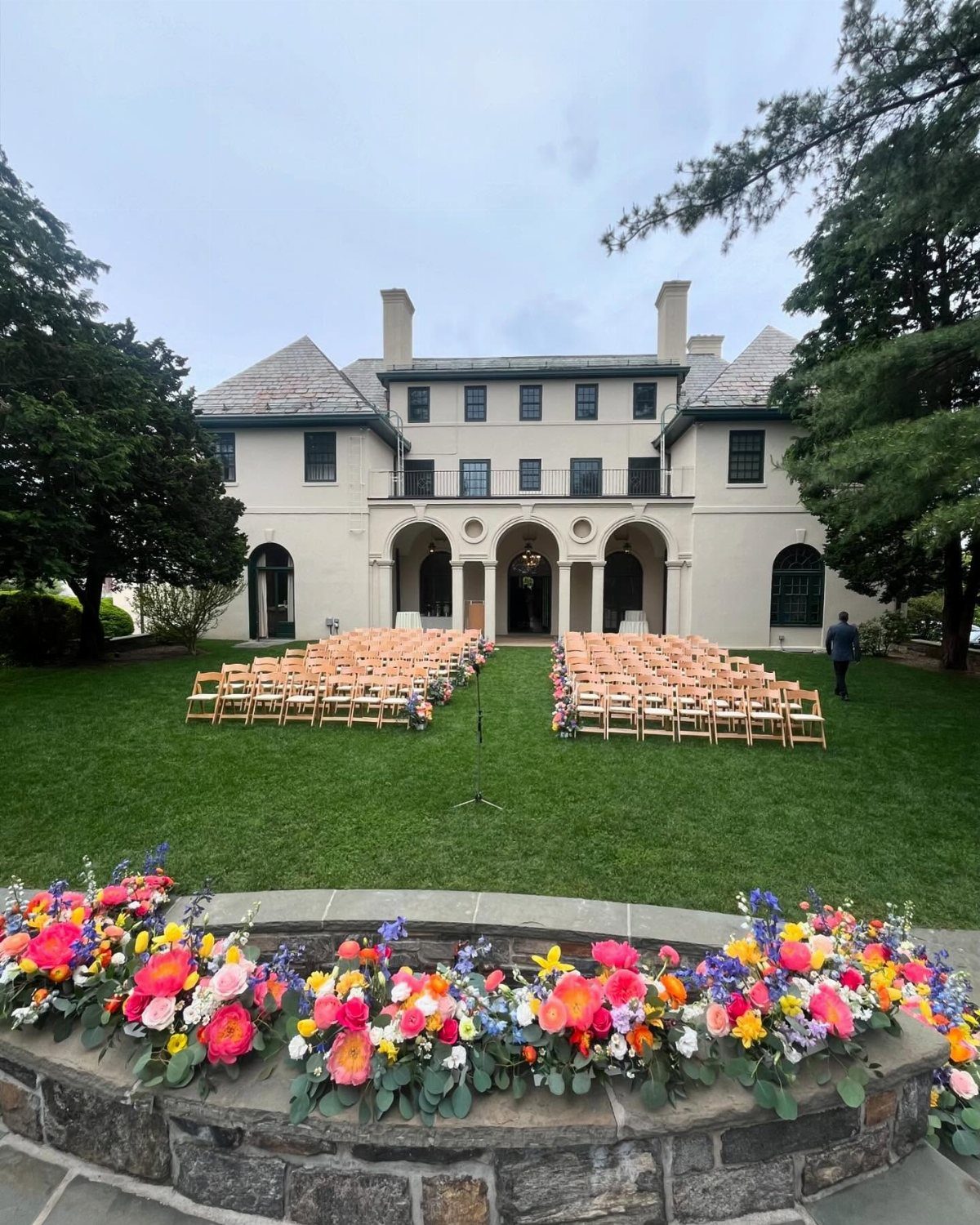 Wedding ceremony setup on a green lawn in front of a white mansion