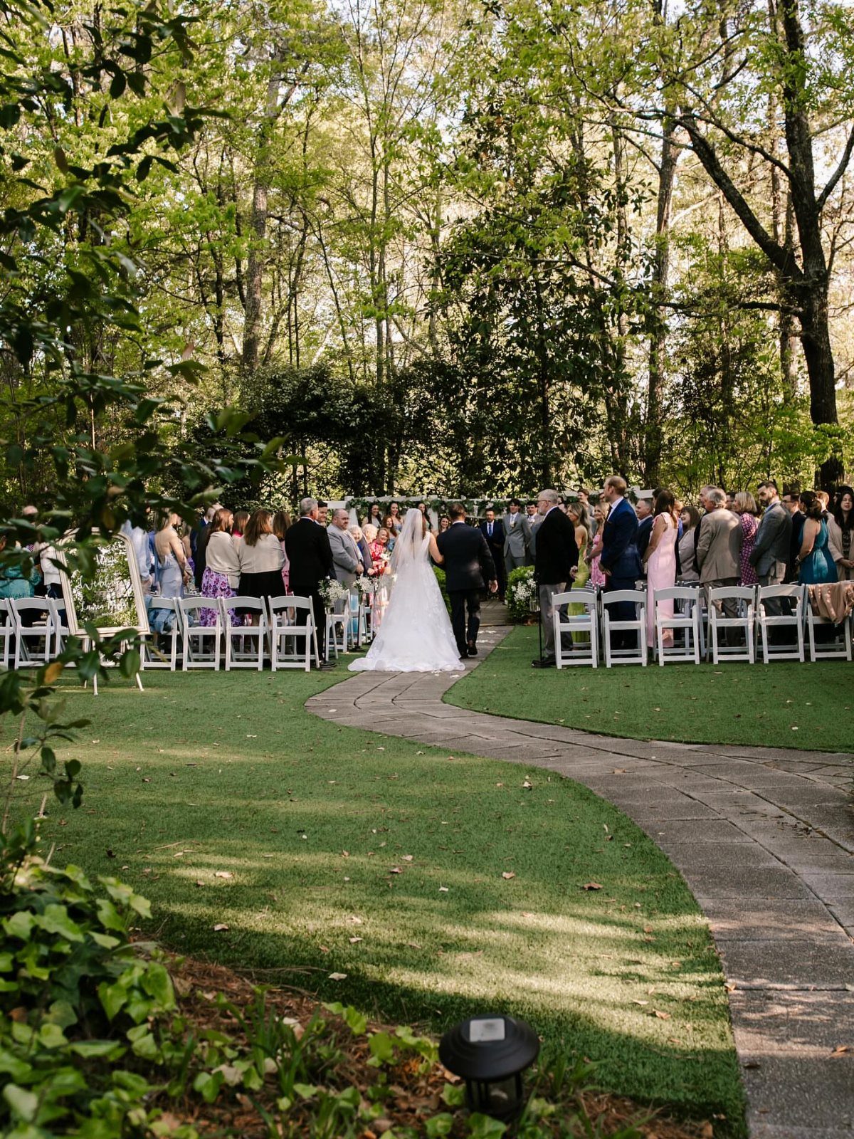 Outdoor wedding ceremony with a bride and groom surrounded by guests in a forest