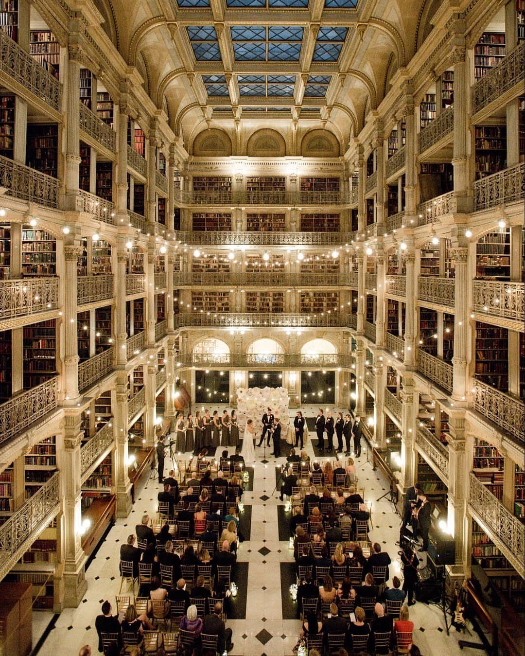 Wedding ceremony in the George Peabody Library with towering bookshelves and ornate architecture.