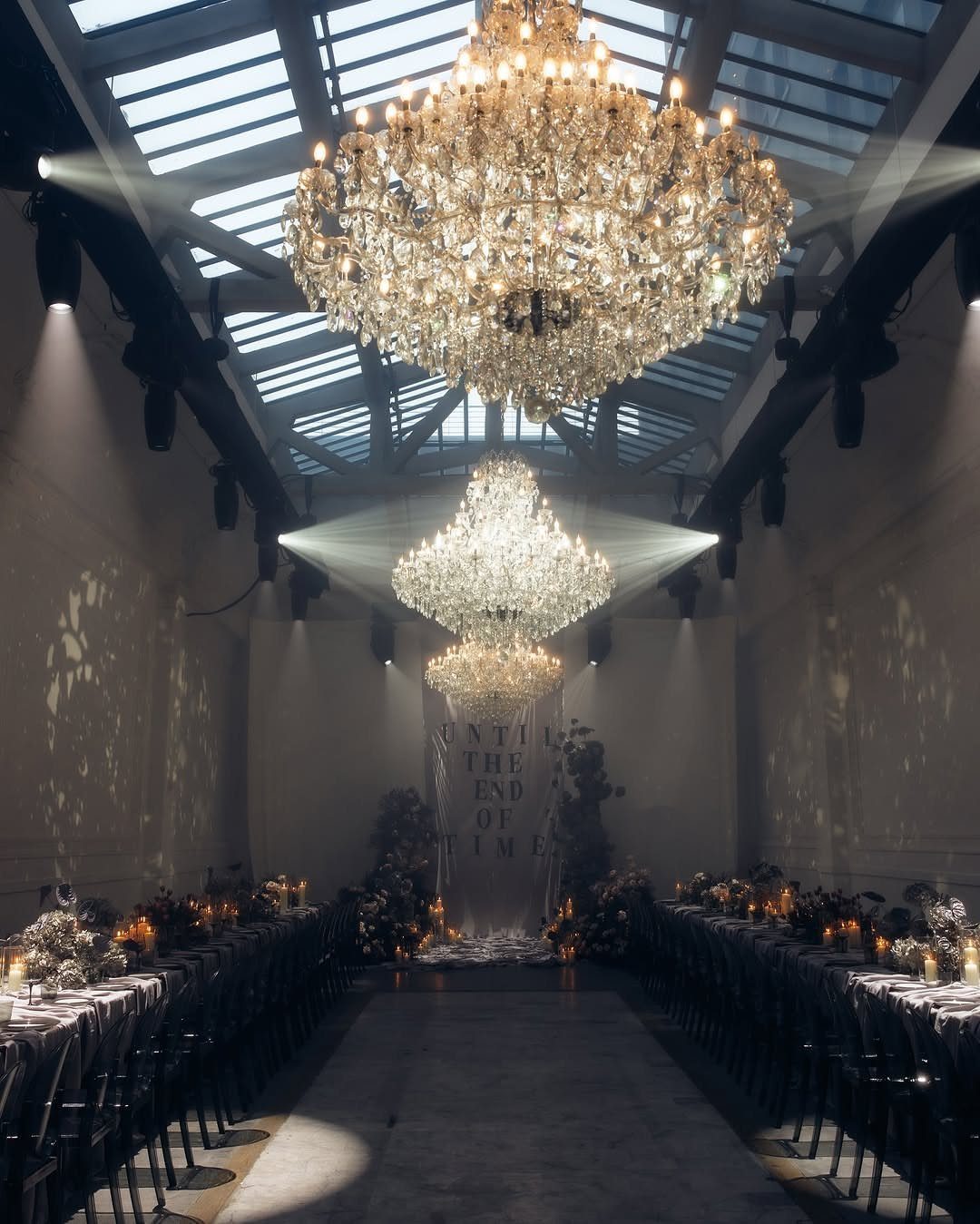 Elegant dining hall with crystal chandeliers, long tables, and a glass ceiling.