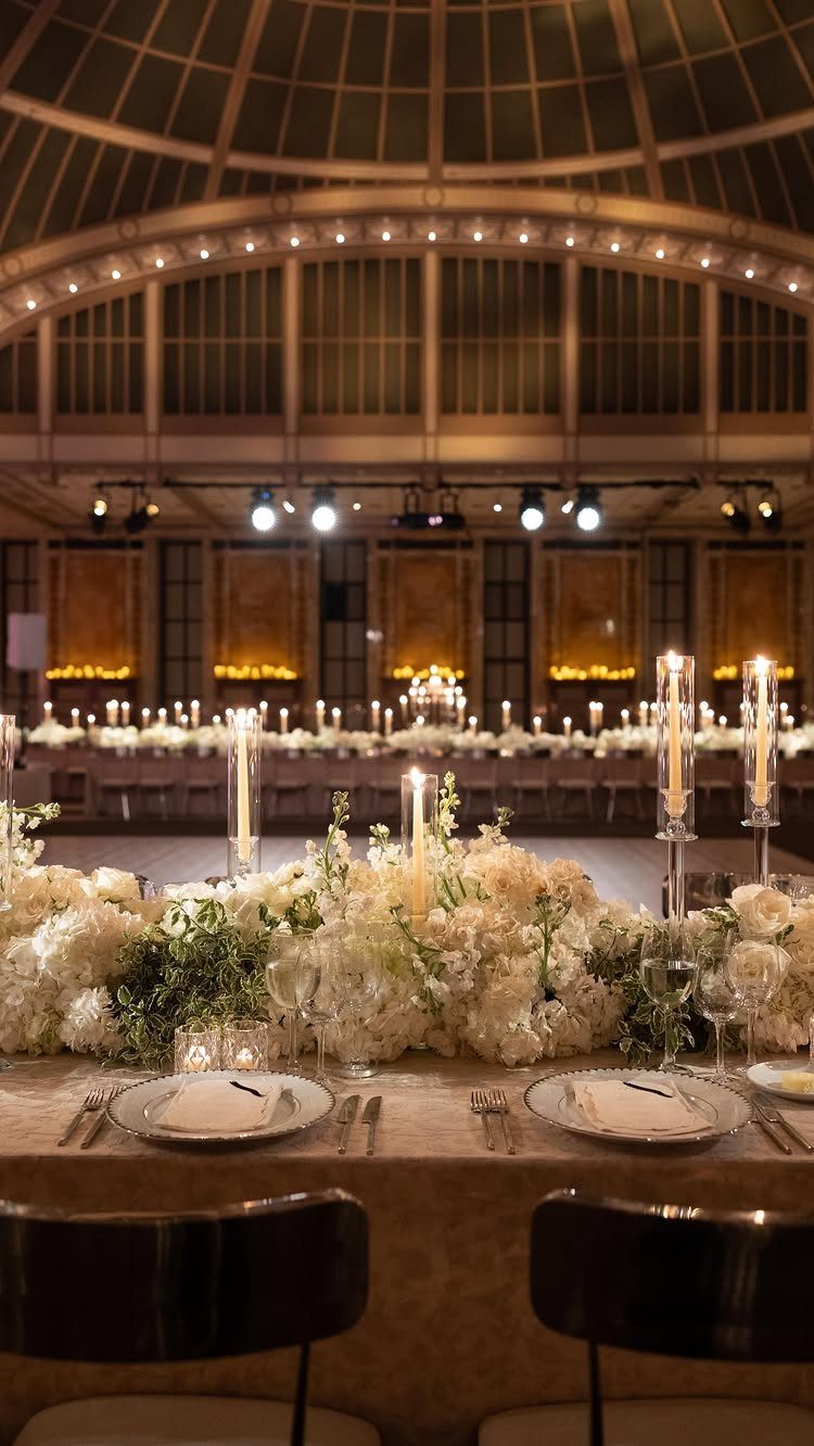 Wedding banquet table with white flowers under a grand curved glass dome ceiling.