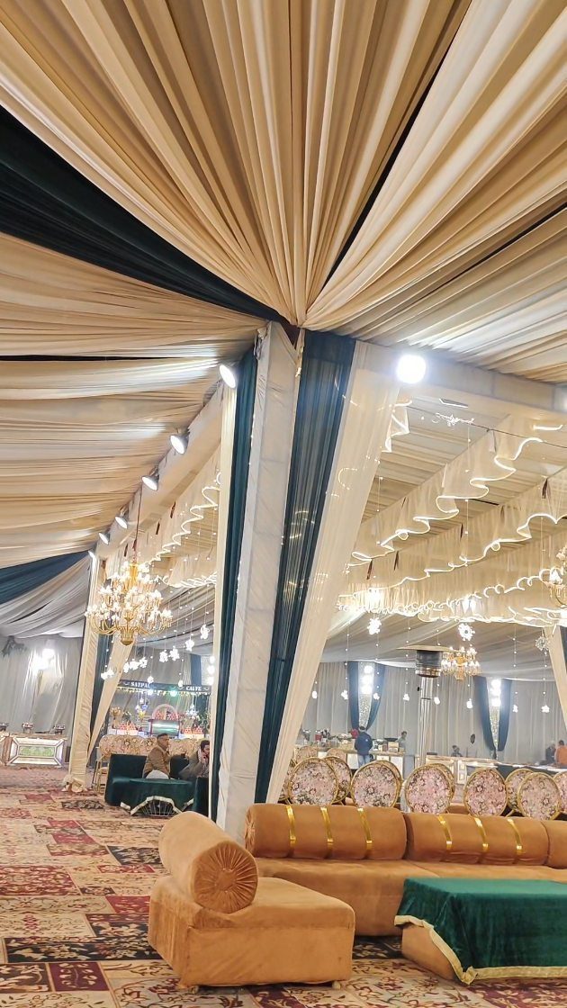 Lavish event venue with draped fabric ceilings, chandeliers, and gold plush seating.