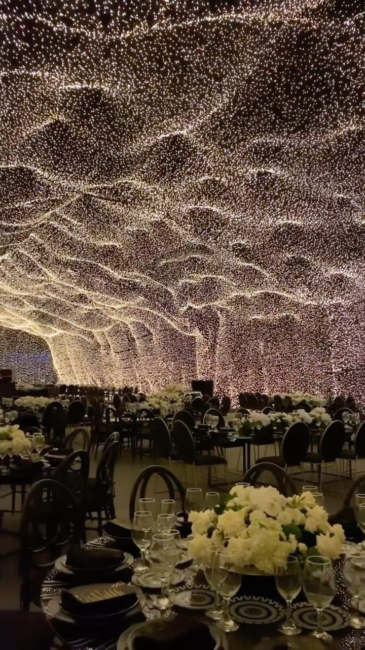 Event dining area with black tables and a ceiling of shimmering fairy lights
