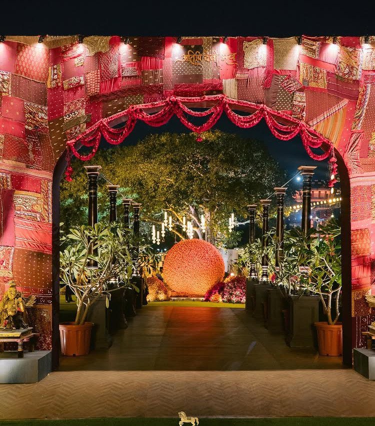Ornate red and gold fabric archway leading to a floral sphere at night
