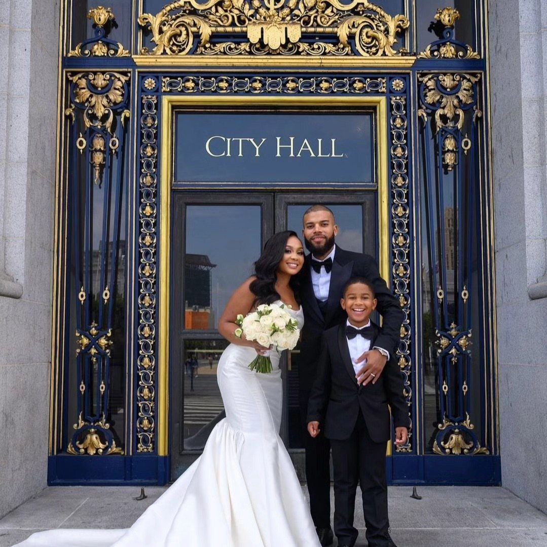 Wedding couple and a young boy posing before a City Hall entrance.