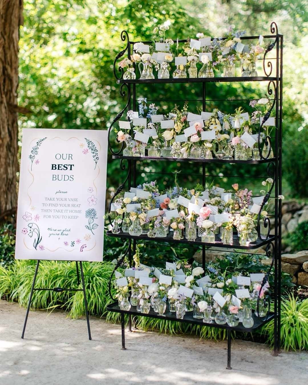 Flower arrangement shelf with name tags and a sign for wedding guests outdoors