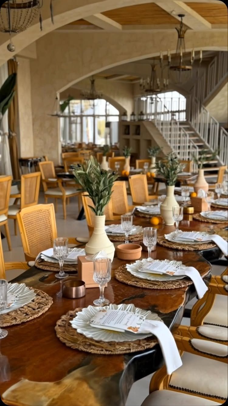 Set dining table with woven placemats and greenery in a bright restaurant interior.