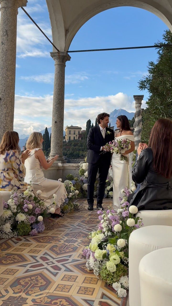 Bride and groom standing together under a stone archway during an intimate wedding ceremony.
